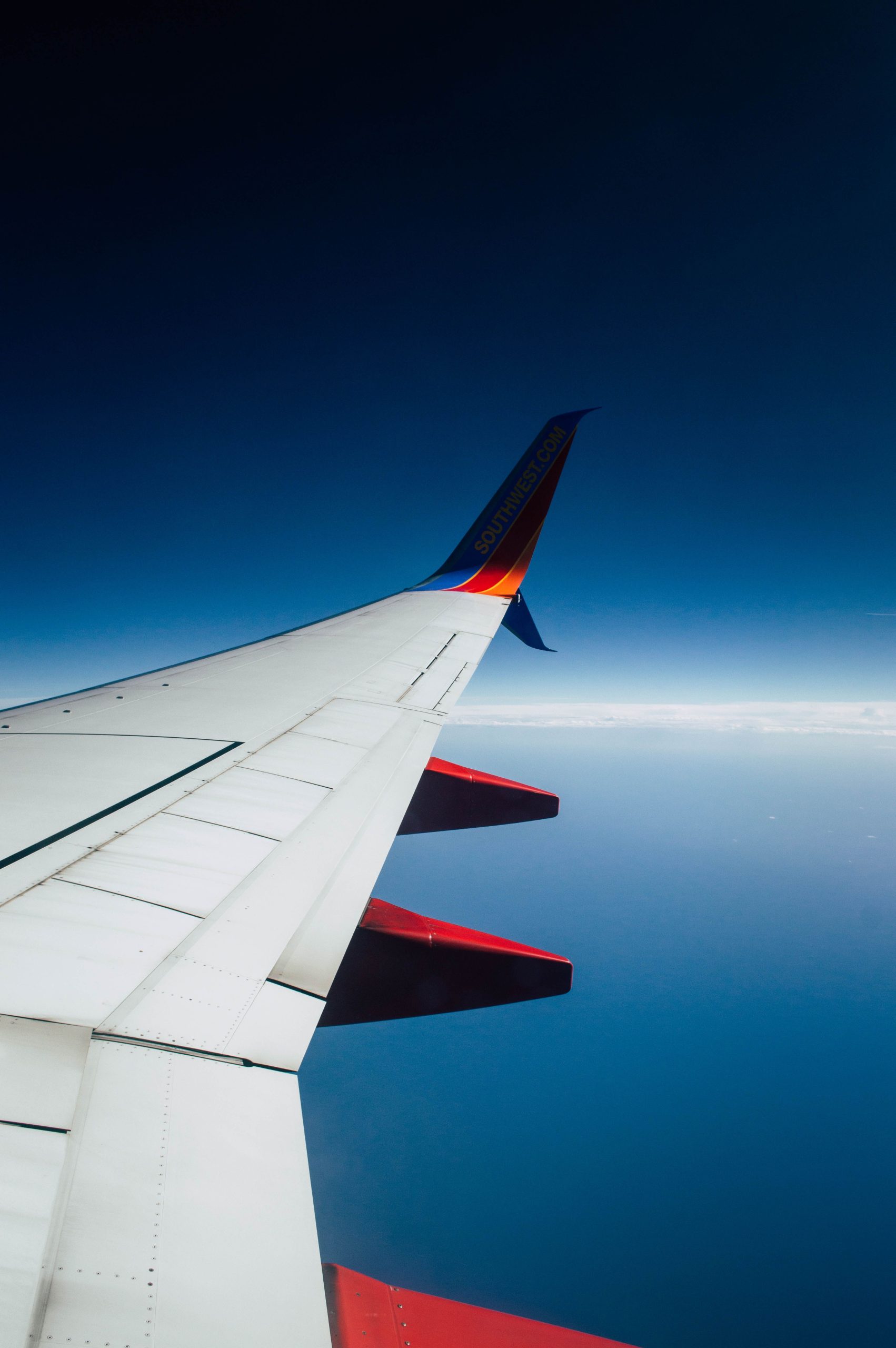 An airplane wing captured in flight against a clear blue sky, showcasing aviation travel